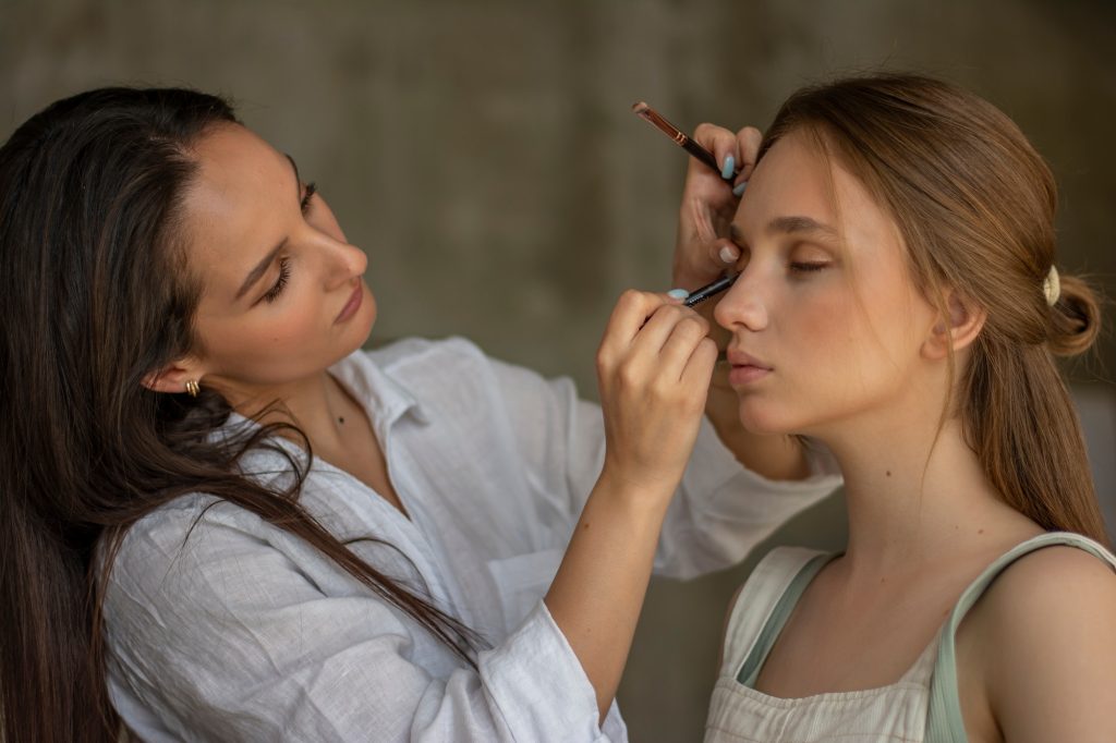 Girl make-up artist makes eye makeup of model