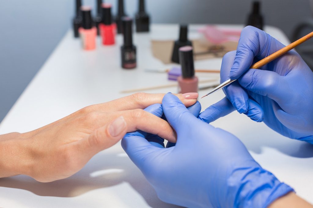 Nails Manicure. The manicurist will remove the coating with the apparatus. Hardware manicure.